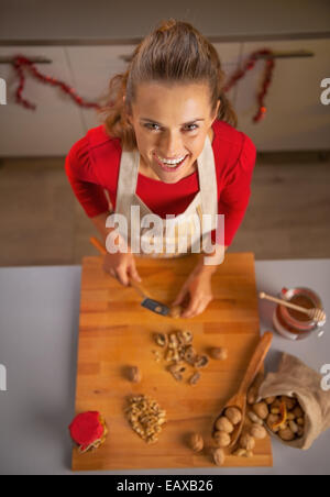 Porträt der glückliche junge Hausfrau, die Walnüsse hacken Stockfoto