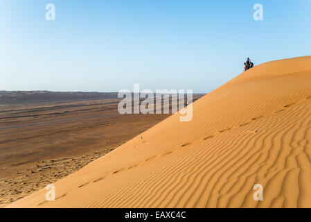 Touristen zu Fuß auf einer Sanddüne in der Wüste von Oman. Stockfoto