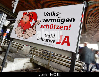 Zürich, Schweiz. 21. November 2014. Menschen im Zürcher Hauptbahnhof sind hinter einem Referendum Wahlplakat der Schweizer "Gold-Initiative" Volksabstimmung übergeben, die am 30. November 2014 stattfinden soll. Mit einer Woche zu gehen wird die Kampagne für das Referendum der Schweizer Gold-Initiative in voller Stärke in der ganzen Schweiz. Das umstrittene Referendum strebt zu zwingen, die Schweizerische Nationalbank, mindestens 20 % aller Vermögenswerte in physisches Gold zu halten. Bildnachweis: Erik Tham/Alamy Live-Nachrichten Stockfoto