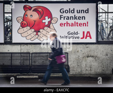 Zürich, Schweiz. 21. November 2014. Menschen im Zürcher Hauptbahnhof sind auf der Durchreise durch Referendum Plakaten das Schweizer Gold-Initiative Referendum am 30. November 2014 stattfinden wird. Mit einer Woche zu gehen wird die Kampagne für das Referendum der Schweizer Gold-Initiative in voller Stärke in der ganzen Schweiz. Das umstrittene Referendum strebt zu zwingen, die Schweizerische Nationalbank, mindestens 20 % aller Vermögenswerte in physisches Gold zu halten. Bildnachweis: Erik Tham/Alamy Live-Nachrichten Stockfoto