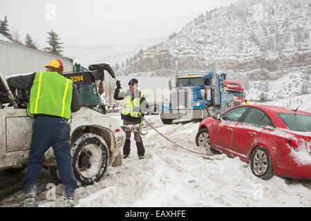 Vail, Colorado - ein Abschleppwagen LKW-Betreiber und Colorado State Patrol Officer vorbereiten, ein Auto aus dem Graben zu ziehen. Stockfoto