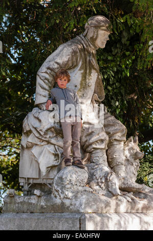 Ein kleiner Junge klettert auf eine Statue in den Biennale-Gärten in Venedig, Italien Stockfoto