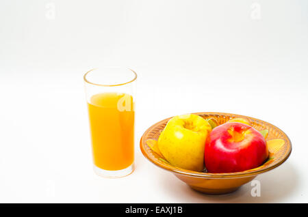 Gebackene Äpfel in eine Schüssel geben und den Saft in einem Glas auf weißem Hintergrund Stockfoto