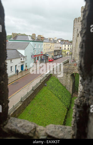 Ansicht der alten Steinmauer des Schlosses, engen Straße mit Reihe von bunten Geschäften & Häuser aus hohen Fenster des Caernarfon castle Stockfoto