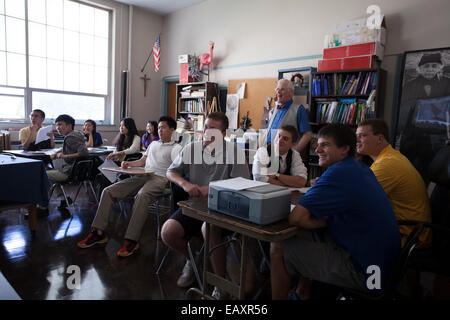 Glückliche Schüler in einem Klassenzimmer katholische High School erfreuen sich ihre Lektion.  Lehrer in der Rückseite des Klassenzimmers. Stockfoto