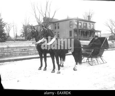 Dieses Vintage-Foto von Bion Whitehouse zeigt einen Mann, der mit einem Pferdeschlitten in Keene, New Hampshire, fährt und die Transportmethoden der Vergangenheit in einer malerischen Winterszene widerspiegelt. Stockfoto