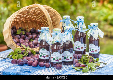 Flaschen mit würziger Pflaumensauce auf Gartentisch Stockfoto