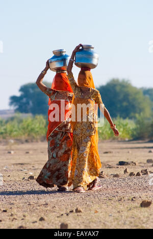 Frauen schleppen einen Wasserkrug auf dem Kopf, um Wasser aus einer natürlichen Quelle zu holen Stockfoto