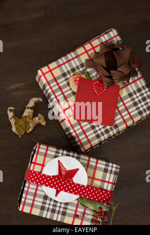Geschenke in karierten Papier eingewickelt und gepunktete Band mit roten Sterne Aufkleber auf hölzernen Hintergrund Stockfoto