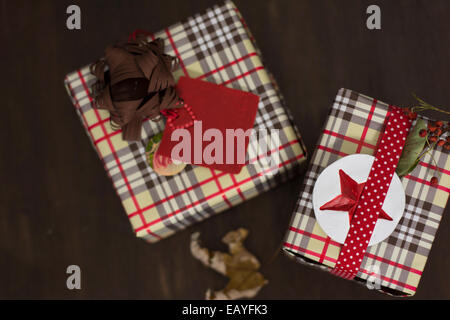 Geschenke in karierten Papier eingewickelt und gepunktete Band mit roten Sterne Aufkleber auf hölzernen Hintergrund Stockfoto
