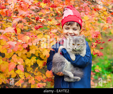 Glücklich lachende Mädchen umarmt eine Katze im Garten im Herbst Stockfoto