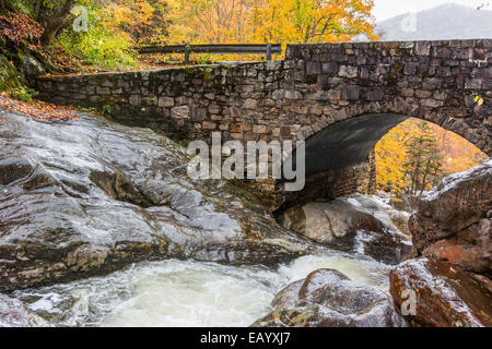 Wasser rauscht unter einer Brücke im Herbst Stockfoto