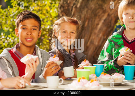 Internationale Kinder trinken Tee mit cupcakes Stockfoto
