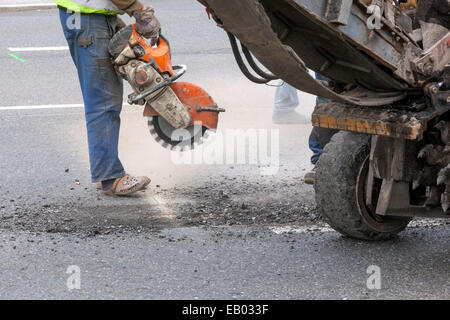 Ein Mann arbeitet Asphalt mit einem Diamond cutter Ausschneiden, keine schützende Arbeit Gang, Tschechische Republik Stockfoto