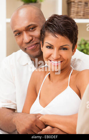 Ein glückliches romantische afroamerikanische Mann und Frau Paar in den Dreißigern sitzen zu Hause umarmen umarmt Stockfoto