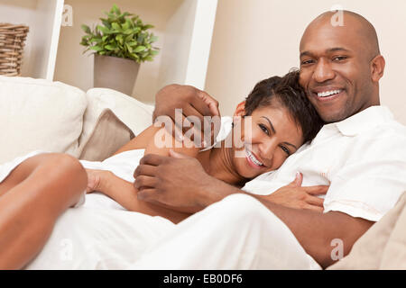 Ein glückliches afroamerikanische Mann und Frau romantische Paar in den Dreißigern, kuscheln, umarmen zu Hause Stockfoto