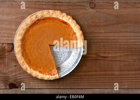 Kürbiskuchen mit einem Stück ausschneiden. Querformat auf einem rustikalen Holztisch. Stockfoto