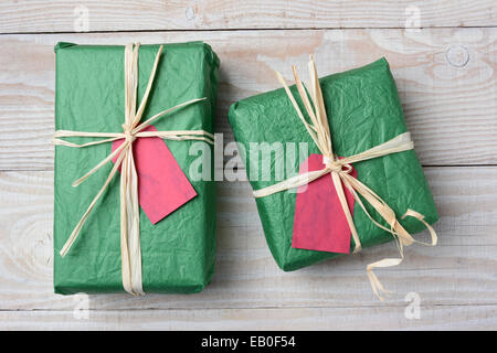 Hohen Winkel Bild von zwei grünen Weihnachtsgeschenke auf einem rustikalen weißer Holztisch. Mit zerknitterten Seidenpapier gewickelt und gebunden mit Stockfoto