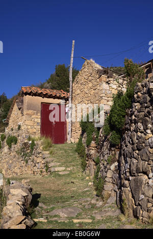 Alte Steinmauern, was zu einem roten Holztor in kleinen traditionellen Aymara Dorf von Sampaya am Titicacasee, Bolivien Stockfoto