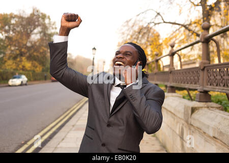 Business-Mann feiert am Telefon. Stockfoto