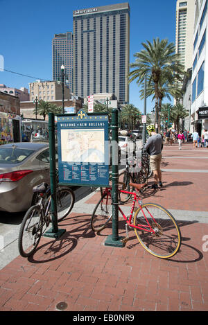 Zyklen, angekettet an Tourist infoBoard und Radfahrer an der Canal Street im Zentrum Stadt New Orleans Louisiana USA Stockfoto