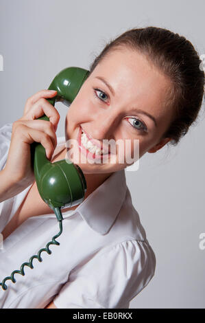 Seitlicher Blick auf eine lächelnde junge Frau, mit einem Vintage grüne Telefon. Stockfoto