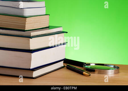 Stapel von Büchern, Stift und Lupe auf Holztisch Stockfoto