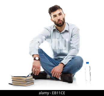 Junge bärtige lächelnden Mann hält ein Tablet mit Büchern und eine Flasche Wasser sitzt auf einem weißen Hintergrund Stockfoto