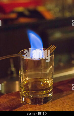 Ein brennendes Stück Würfelzucker in einem Glas Absinth Veranschaulichung der französischen Tropfenfänger-Methode. Stockfoto