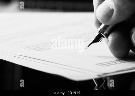 Eine Hand hält ein Füllfederhalter und einen Brief zu unterzeichnen. Styling und kleine Menge an Getreide angewendet. Stockfoto