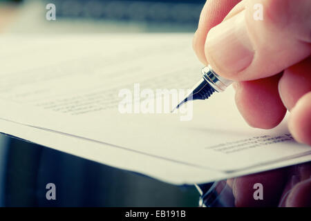 Eine Hand hält ein Füllfederhalter und einen Brief zu unterzeichnen. Styling und kleine Menge an Getreide angewendet. Stockfoto