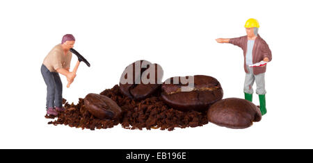 Miniatur-Arbeiter mit Spitzhacke arbeitet an einer Kaffeebohne Stockfoto