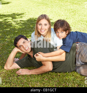 Glückliche Familie mit Sohn Verlegung im Sommer Gras eines Gartens Stockfoto