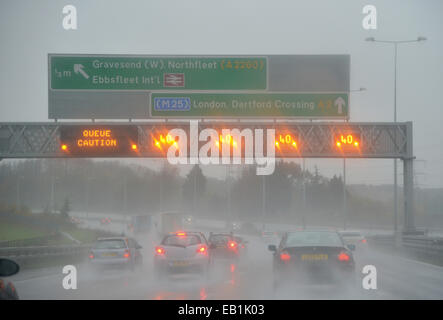 Geschwindigkeitsbegrenzungen und Warteschlange Warnzeichen leuchtet bei strömendem Regen über die M2-Autobahn im Vereinigten Königreich Stockfoto