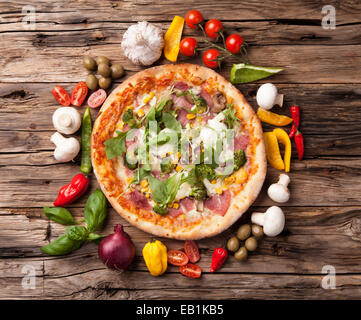 Leckere frische Pizza serviert auf Holztisch mit Zutaten aller Stockfoto