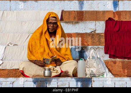 Ein Mann sitzt auf den Ghats, lesen ein Buch, Varanasi, Uttar Pradesh, Indien Stockfoto