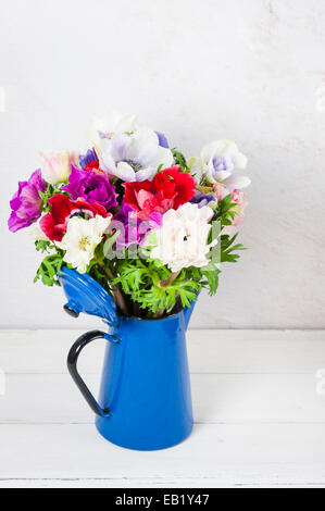 Rosenstrauss bunte Anemonen in einem Vintage blauer Emaille Kaffee-Topf auf dem weißen Putz Wand Hintergrund Stockfoto