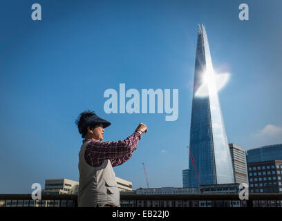 Von der Seite des "Splitter" Skyscaper wie eine orientalische Frauen Tourist ein Foto nimmt das Sonnenlicht reflektiert. Stockfoto