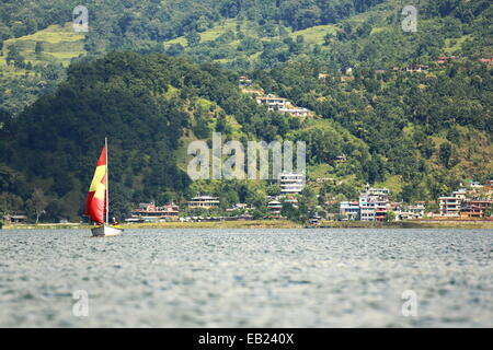 POKHARA, NEPAL - Oktober 12: Touristische Frauen Segeln die Gewässer des Phewa See auf einem Racing-Segelboot mit roten und gelben Segeln. Stockfoto