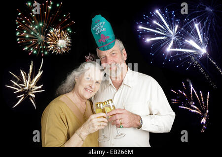 Schönes älteres Paar feiert ein frohes neues Jahr mit einem Champagner anstoßen, während Feuerwerk in den Hintergrund losgehen. Stockfoto