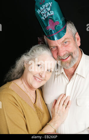 Schönes paar die sechzig posiert für ein romantisches Portrait auf Silvester.  Schwarzer Hintergrund. Stockfoto