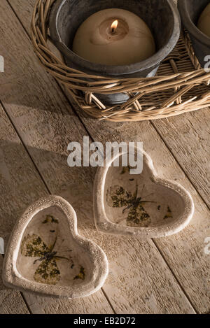 Zwei dekorative hört aus Stein Ware in Form von kleinen Tassen oder Inhaber auf einem weißen gewaschenen Holztisch neben einem bur Stockfoto