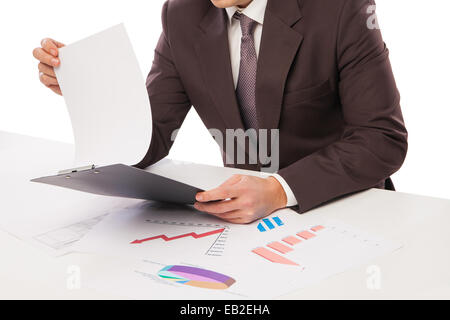Mann trägt Anzug sitzt im Schreibtisch beobachten Haufen von Diagrammen Stockfoto
