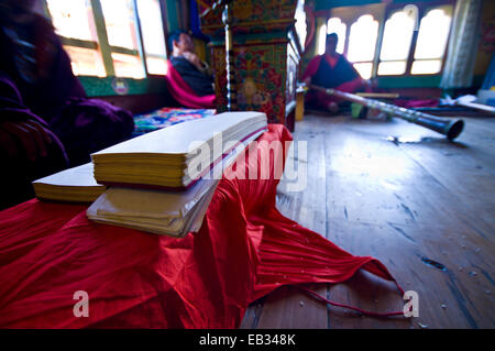 Haufen von Pergament in Sanskrit Text gespielt von buddhistischen Mönchen auf Langhorn Hörner Preisverleihung Tod in einem bhutanischen Haus abgedeckt. Stockfoto