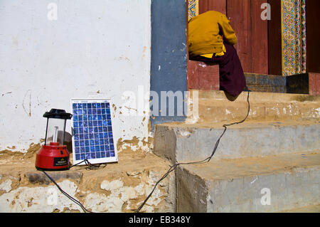 Ein buddhistischer Mönch in einem Kloster versucht ein Solar-Panel zum Aufladen von seinem Handy und camping Lampe zu beheben. Stockfoto