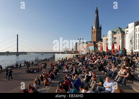 Leute sitzen auf einer Treppe in der Abendsonne, Burgplatz Platz mit St. Lambertus Kirche, Altstadt, Düsseldorf Stockfoto