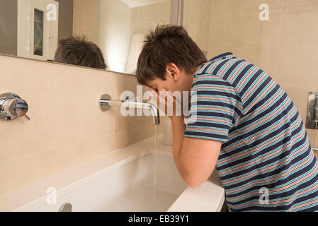 kleiner Junge im Pyjama sein Gesicht waschen Stockfoto