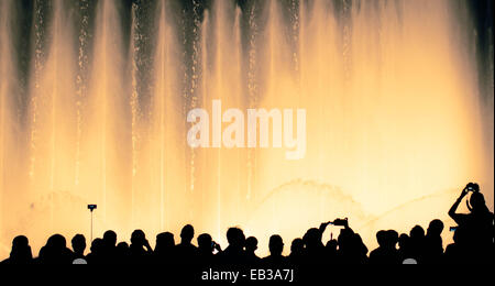 Silhouette von Menschen vor einem beleuchteten Wasserbrunnen Stockfoto