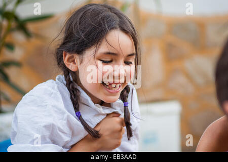 Kleines Mädchen mit Zöpfen und weißes Hemd glücklich lachend (6-7) Stockfoto