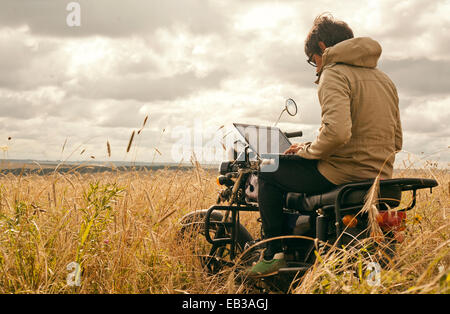Mari Mann mit Laptop auf dem Motorrad im ländlichen Bereich Stockfoto